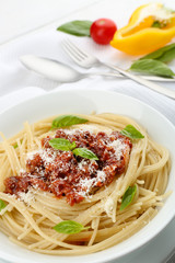 Spaghetti Bolognese with parmesan cheese in white bowl, on color wooden background