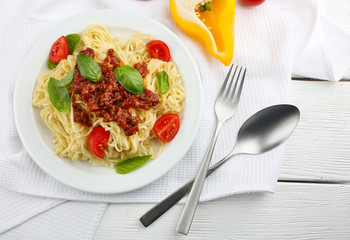 Spaghetti Bolognese on white plate, on color wooden background