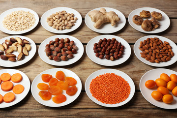 Different products on saucers on wooden table close up