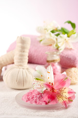 Massage bags with spa treatment and flowers on wooden table, on light background