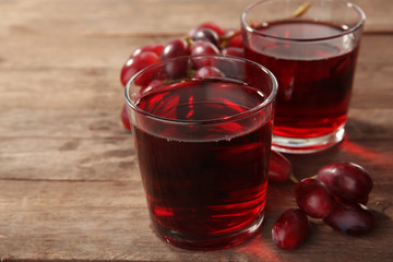 Glass of grape juice on wooden background