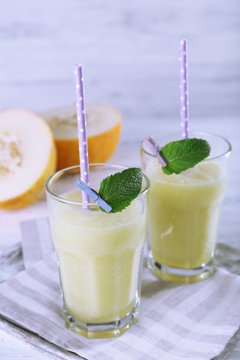 Glasses of melon cocktail on white wooden background