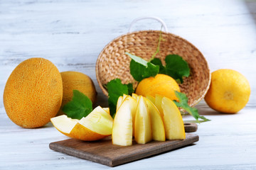 Slices of ripe melons with green leaves on table close up