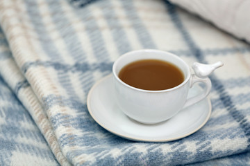 Cup of coffee on sofa in living room