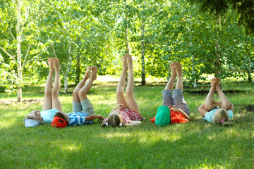 Happy active children lying on green grass in park