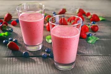 Glasses of berry smoothie on wooden table, closeup