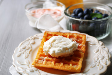 Sweet homemade waffles on plate, on color wooden background