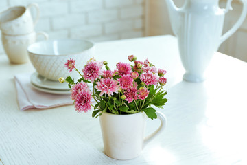 Beautiful flowers in decorative vase on table, on light background