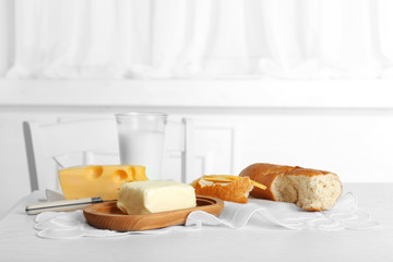 Fresh bread with cheese and butter on table in kitchen