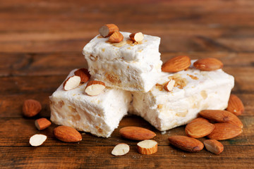 Sweet nougat with almonds on wooden background