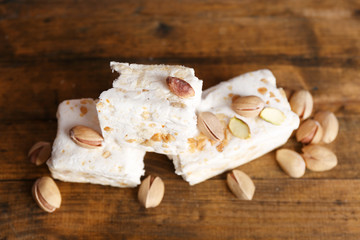 Sweet nougat with pistachios on wooden background