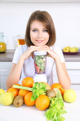 Young beautiful woman using blender, preparing orange juice