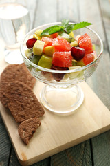 Fruit salad in glass bowl, on wooden background