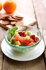 Fruit salad in glass bowl, on  wooden background