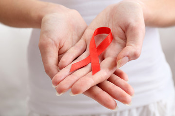 Female hands holding red ribbon sign, closeup
