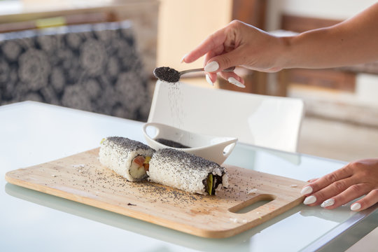 Woman dressing sushi roll with poppy