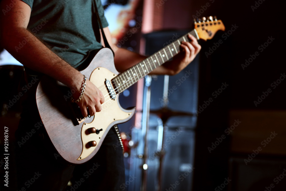 Wall mural young man playing on electric guitar close up