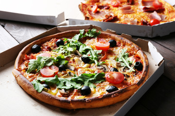 Pizza in box on wooden table closeup