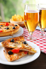 Sliced pizza served with beer on wooden table