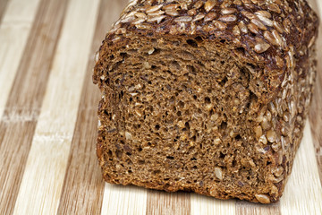 Rye bread mixed from many different healthy ingredients like pieces of soy, rye and wheat flour, sunflower seeds and barley. Studio shot. Photographed on interesting wooden table.