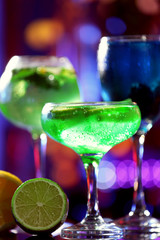 Glasses of cocktails on bar background