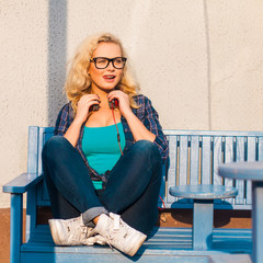 Obraz premium young girl in glusses with headphones sitting on a bench near the cafe