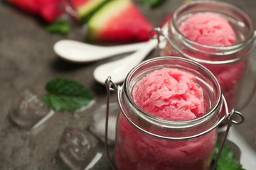 Watermelon ice cream in glass jars on dark background