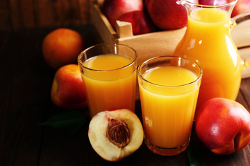 Peach juice and ripe peaches on wooden background