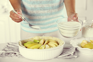 Woman making apple pie on wooden table, on light background