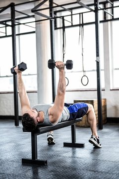 Fit man lifting heavy black dumbbells