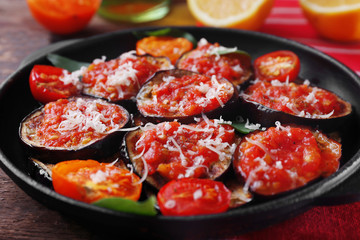 Baked vegetables in pan on wooden table, close up