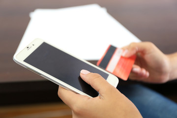 Woman verifies account balance on smartphone with mobile banking application on wooden table background