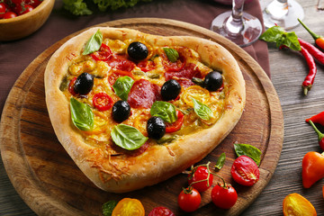 Heart shaped pizza served on wooden table, closeup