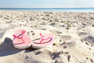 Fototapeta na wymiar Flip flops on beach sand closeup