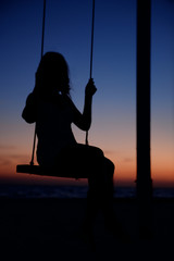 Woman on swing on sunset beach