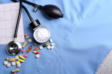 Blood pressure meter, pills and stethoscope, on blue uniform background