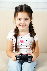 Happy Caucasian girl playing video games holding game controller sitting  on coach living room