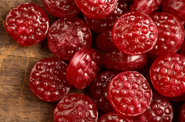 Pile of tasty delicious raspberry hard candy lying on wooden