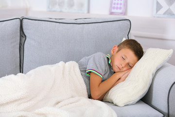 Little boy sleeping on sofa in room