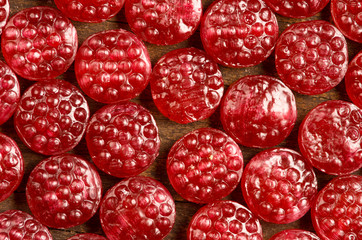 Pile of tasty delicious raspberry hard candy lying on wooden