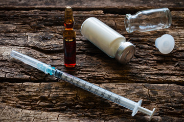 Medical syringe and ampoules on a wooden background
