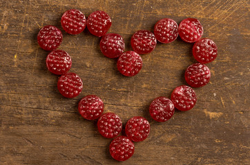 Lovely heart made out of raspberry hard candy on wooden surface