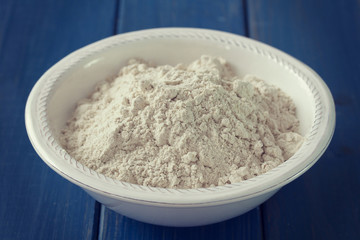 powder on white plate on blue wooden background