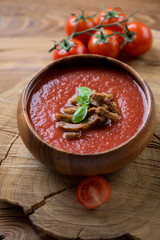 Gazpacho soup with croutons and green basil in a wooden bowl
