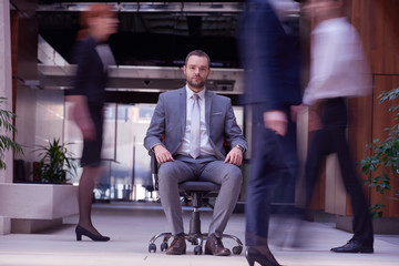 Obraz premium business man sitting in office chair, people group passing by