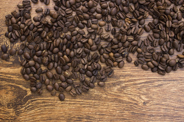 Whole aromatic coffee beans on a wooden background closeup