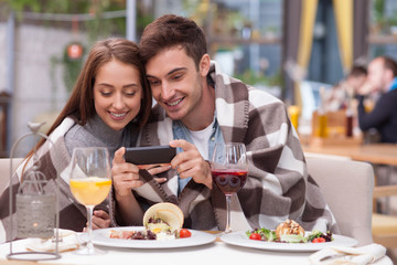 Beautiful young loving couple is using telephone in cafe