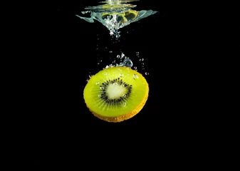 Poster Piece of sliced kiwifruit in the water isolated from black background © topstep07