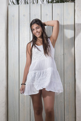 Fototapeta premium Close view of a beautiful woman on a white dress against a white wooden door.