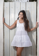 Close view of a beautiful woman on a white dress against a white wooden door.